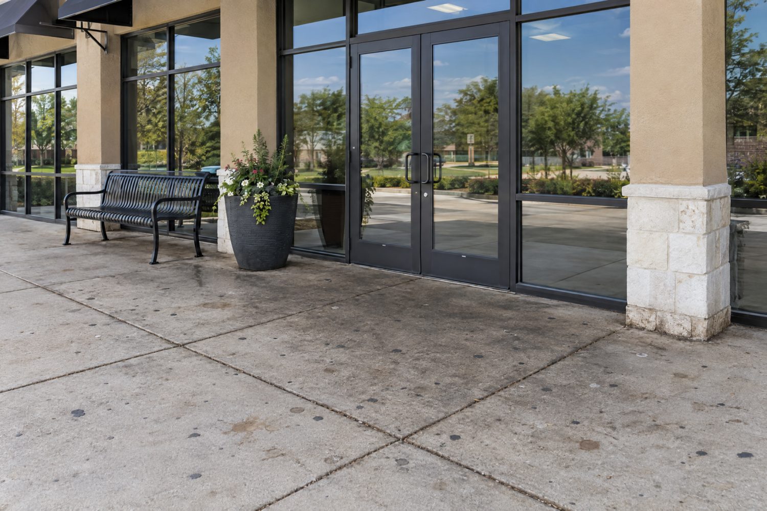 A storefront sidewalk covered in gum spots and grime