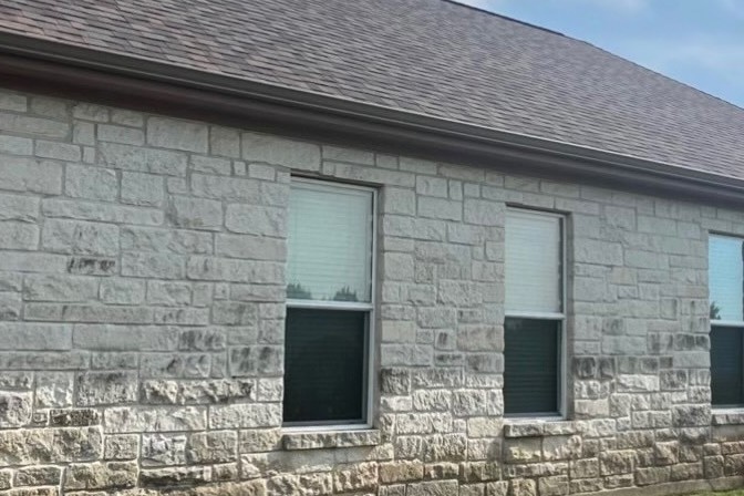 A stone house wall streaked grey with mildew
