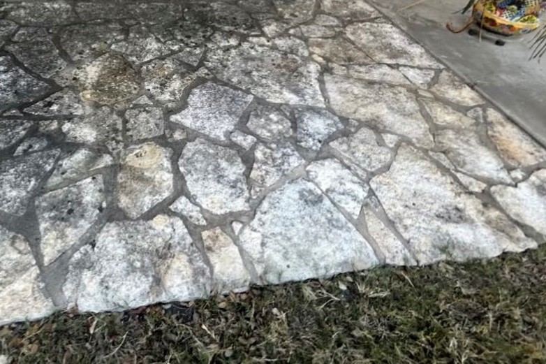 A flagstone patio grey with grime