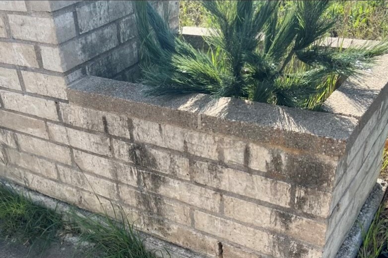 A brick planter stained dark along every course